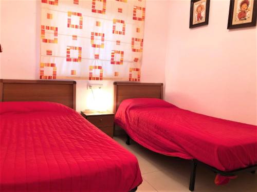 2 Betten in einem Zimmer mit roter Bettwäsche in der Unterkunft ACV - Vistamar II-1ª línea planta 1 norte in Oropesa del Mar