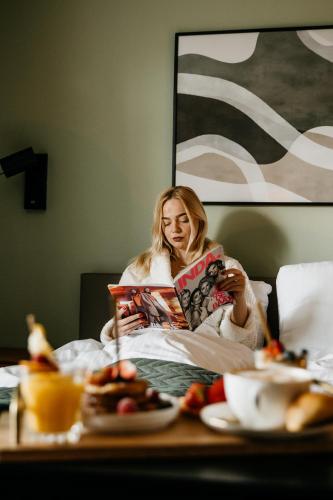 a woman sitting in bed reading a book at Hotel Janssen in Valkenburg
