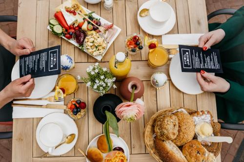 people sitting around a wooden table with breakfast food at Hotel Janssen in Valkenburg