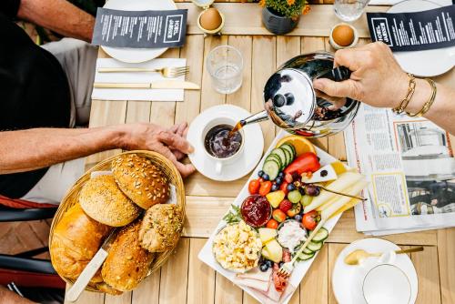 una mesa con platos de comida y gente bebiendo té en Hotel Janssen, en Valkenburg