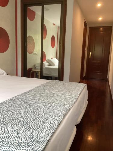 a bedroom with a white bed and a mirror at Saudade Hostal Cafetería in A Coruña