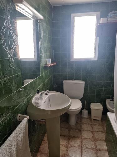 a green tiled bathroom with a sink and a toilet at APARTAMENTO LEO in Benicarló