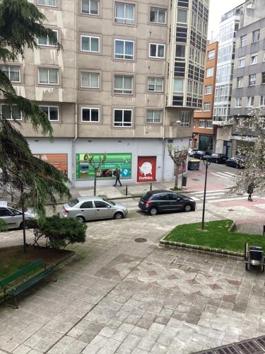 a parking lot with cars parked in front of a building at Saudade Hostal Cafetería in A Coruña