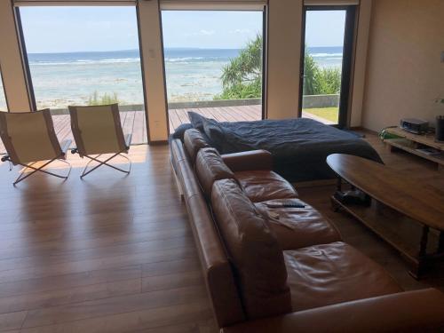 a living room with a couch and a bed and the ocean at ゴールデンマイルヴィラ in Amami