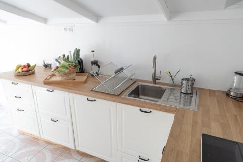 a kitchen with white cabinets and a counter with a sink at GITES CURCUMA et COMPAGNIE in Jumencourt