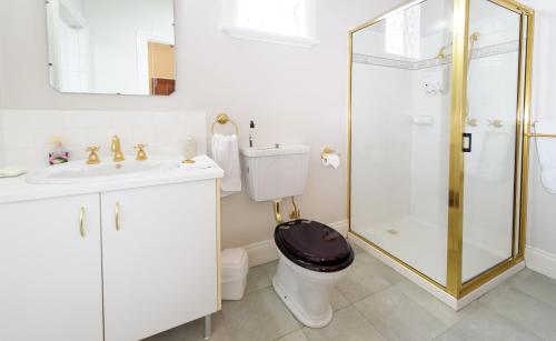 a bathroom with a toilet and a sink and a shower at Montfort Manor in Traralgon