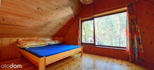 uma cama num chalé de madeira com uma janela em Dom całoroczny w Borach Tucholskich em Klocek