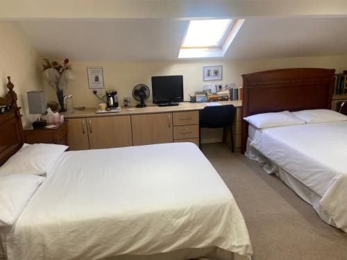 a bedroom with two beds and a desk with a television at Top of the House! in Manchester
