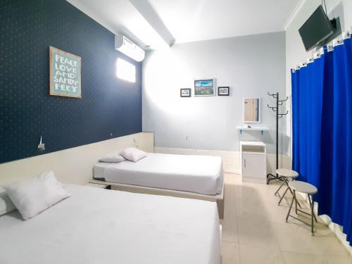um quarto com 2 camas e uma cortina azul em Londres Bed and Breakfast RedPartner near Gembira Loka Zoo em Yogyakarta