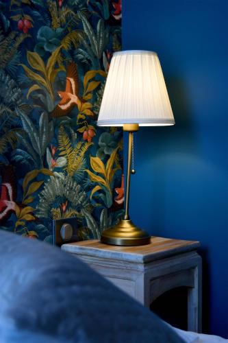 a lamp on a table in a bedroom with a wallpaper at Hôtel Le Tiburon in Cherbourg en Cotentin