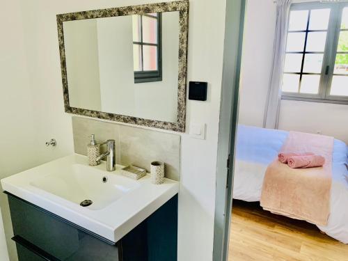 une salle de bain avec un lavabo, un miroir et un lit dans l'établissement Les Grands Bois, à Pomport