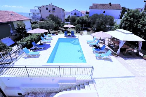 una piscina con tumbonas y sombrillas en Villa Mendula Trogir - Luxury beachfront villa with large pool area surrounded by organic vegetable garden and olive trees en Trogir