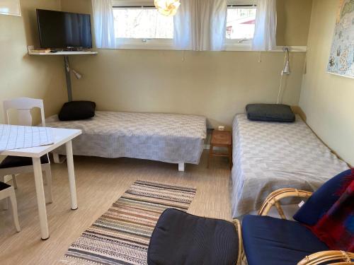 a room with two beds and a table and a tv at Studio Kustvägen in Mellbystrand