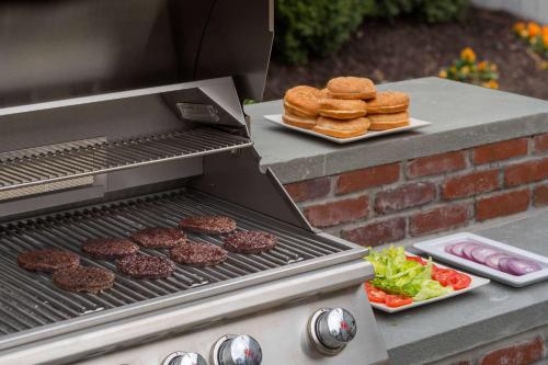a grill with hamburgers and burgers and a plate of food at Sonesta ES Suites San Antonio Northwest Medical Center in San Antonio