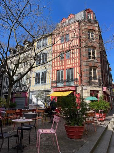 a building with tables and chairs in front of it at Hôtel Paulette Rouen Centre Cathédrale in Rouen