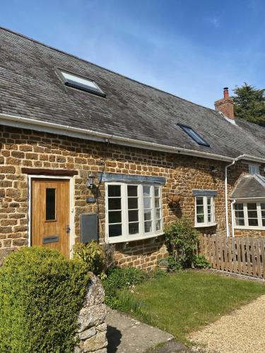 a brick house with a wooden door and windows at The Red Lion at Hellidon in Daventry