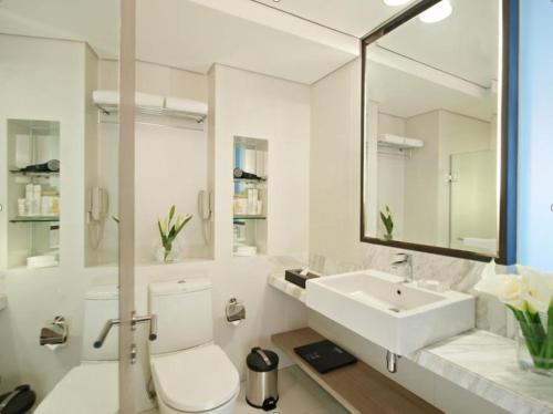 a white bathroom with a toilet and a sink at Seda Centrio in Cagayan de Oro
