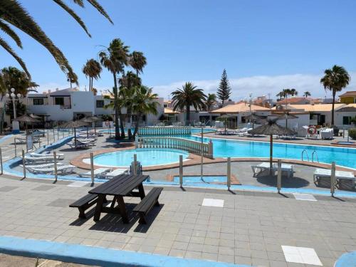 una piscina con un banco de madera frente a ella en Puerta del Sol II (Caleta de Fuste), en Caleta de Fuste