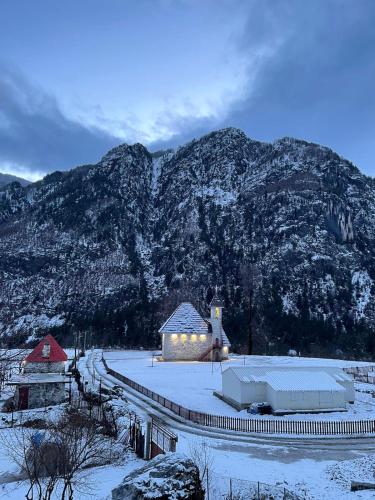 a building with snow on it in front of a mountain at Guesthouse Prrockaj Theth in Theth