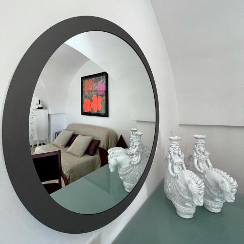 a mirror in a room with a bed and vases at Bartago Luxury House in Ostuni