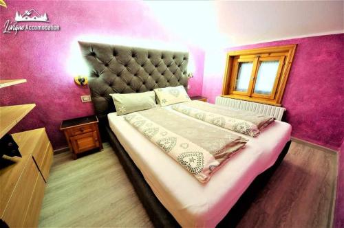 - une chambre avec un grand lit et un mur rose dans l'établissement Residence Casa Longa, à Livigno