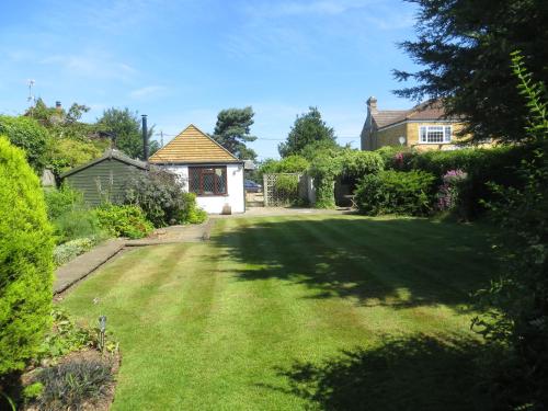 un patio con un gran césped frente a una casa en Willow Cottage, en Dersingham