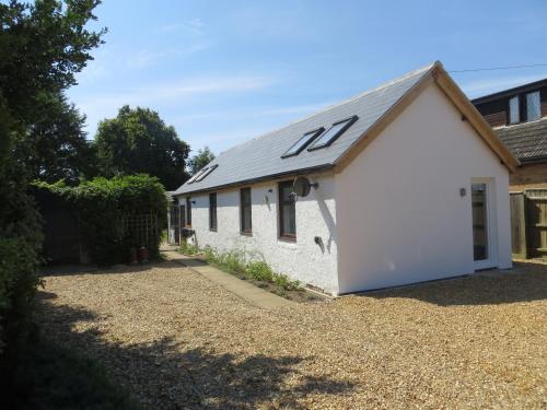 a white building with a roof with the number on it at Willow Cottage in Dersingham