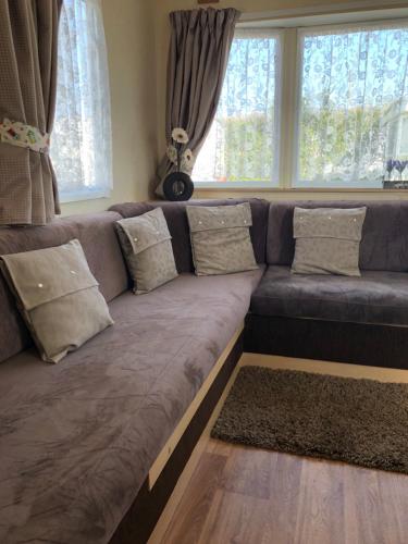 a large couch in a living room with windows at Norfolk Lavender Caravan - Sleeps 4 - WiFi and Sky TV Included in Bacton