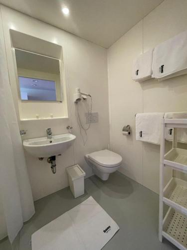 a white bathroom with a toilet and a sink at SOVEA Hotel - Braunau in Braunau am Inn