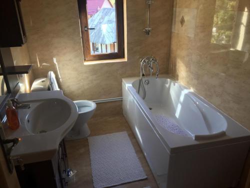 ein Badezimmer mit Badewanne, Toilette und Waschbecken in der Unterkunft Casa Cris in Durau