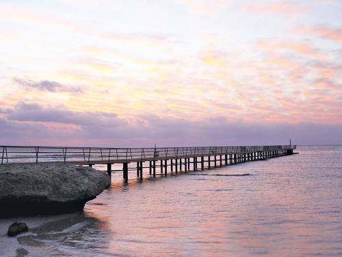 a pier in the ocean with a person standing on it at Pickalbatros The Palace Port Ghalib in Port Ghalib