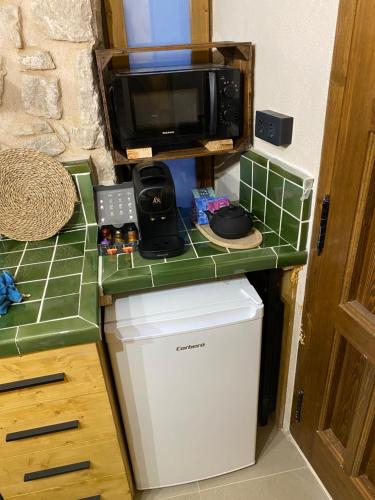 a kitchen with a counter with a microwave and a refrigerator at Precioso loft rural con estufa de leña panorámica in Torre del Compte