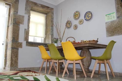 a dining room with a table with yellow and green chairs at Casa Moiano in Oliveira do Hospital