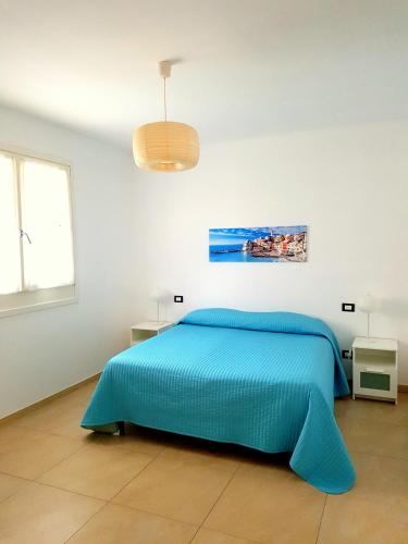a bed in a white room with a blue bedspread at Al Molino delle Ghiare in Levanto