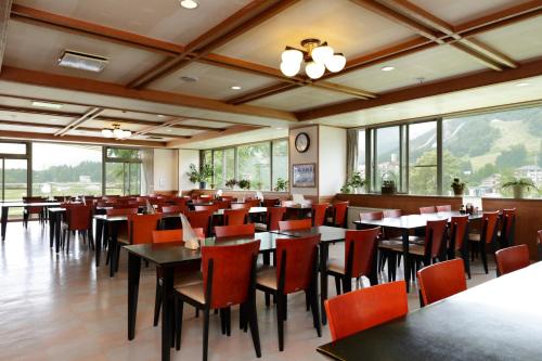 a dining room with tables and chairs and windows at Happokan in Hakuba