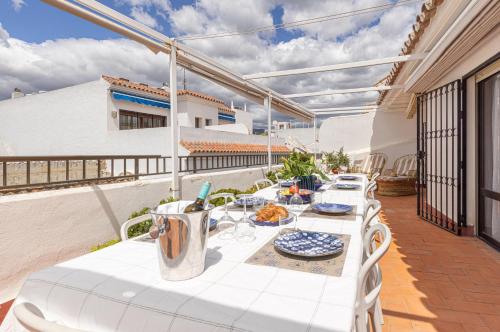 a table with white chairs and food on a balcony at La Casa de Manuel in Estepona