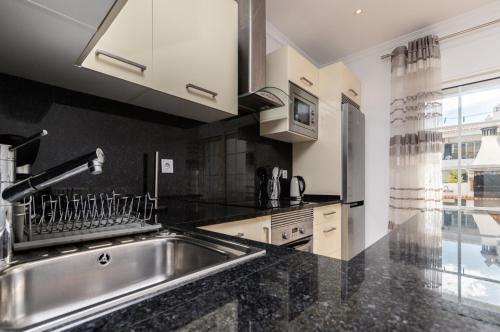 a kitchen with a sink and a large window at Akisol Albufeira Water in Albufeira