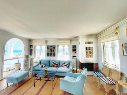 ein Wohnzimmer mit einem blauen Sofa und Stühlen in der Unterkunft Vue Imprenable Le balcon de tanger in Tangier