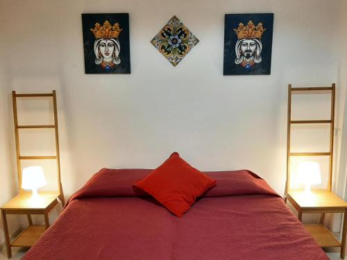 una camera con un letto rosso con tre immagini sul muro di Casa di Giù a Scicli
