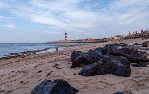 a beach with rocks and a lighthouse in the background at Dwarkadhish Lords Eco Inn in Dwarka