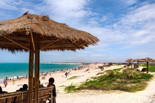 a beach with a straw umbrella and a crowd of people at Dwarkadhish Lords Eco Inn in Dwarka