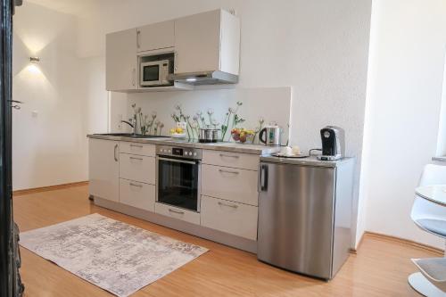 eine Küche mit einem Kühlschrank aus Edelstahl und einer Mikrowelle in der Unterkunft Apartments am Prinzenplatz - Superior in Kamp-Lintfort