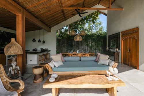 a living room with a blue couch and a table at Villa Kikaa Bingin in Uluwatu