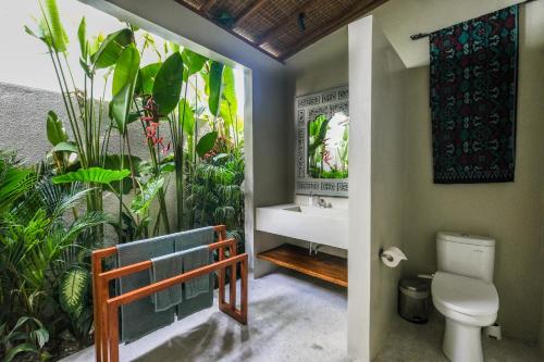 a bathroom with a toilet and a sink and plants at Villa Kikaa Bingin in Uluwatu