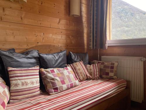 uma cama com almofadas num quarto com uma janela em Appartement 4/6 pers 38m2, vue montagne, piscine chauffée, 500m centre ville em Cauterets