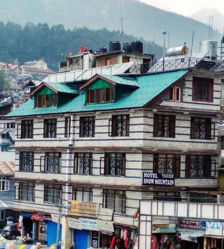 a building with a blue roof on top of it at Hotel Snow Mountain Mall Road in Manāli
