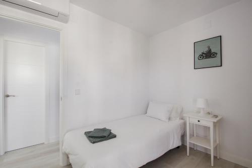 a white bedroom with a white bed and a table at Dulce Barrosa Mar Beach Front in Chiclana de la Frontera