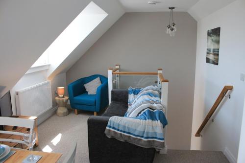 a attic room with a bed and a blue chair at Sea dream lodge -coastal location/sea views/self-contained in Southerndown