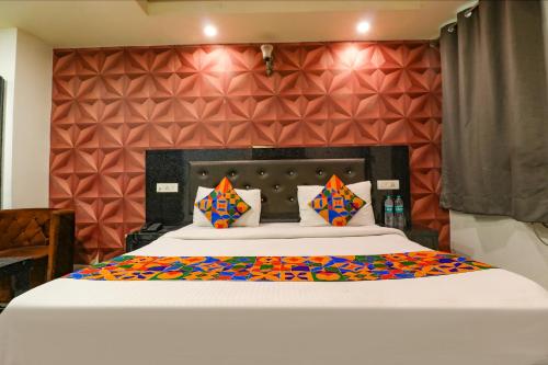 1 dormitorio con 1 cama blanca grande con almohadas coloridas en FabHotel A One Noida Sector 11, en Noida