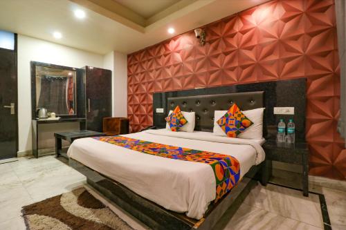 um quarto com uma cama grande e uma parede vermelha em FabHotel A One Noida Sector 11 em Noida